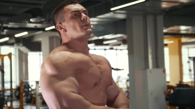 Strong muscular shirtless man in front of mirror in a gym