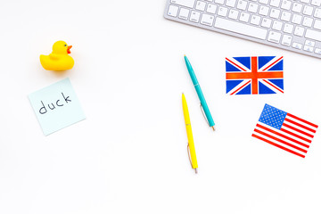 English for children. British and american flags, computer keyboard, stickers with vocabulary, toy on white background top view copy space