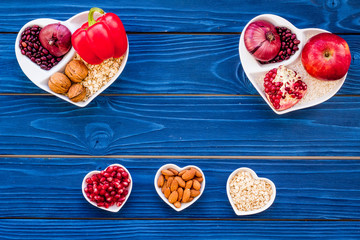 Food which help heart stay healthy. Vegetables, fruits, nuts in heart shaped bowl on blue wooden background top view copy space