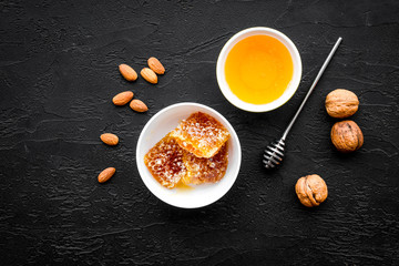 Fresh honey as dessert. Honey in bowl, honeycomb, nuts on black table top view copy space