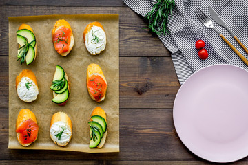 homemade sandwiches with french baguette, salmon, cheese and vegetable on wooden background top view mock-up