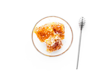 Honeycomb filled with honey on plate on white background top view