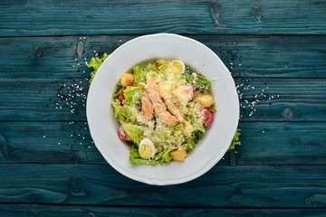 Chicken Salad and Fresh Vegetables. Caesar. Top view. On a blue wooden background. Copy space.