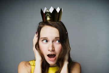 a young blue-eyed girl in a yellow dress covered her ears with her hands and looks surprised, a...