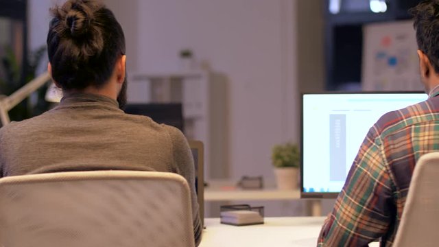 deadline, technology and people concept - programmers with computers working together late at night office