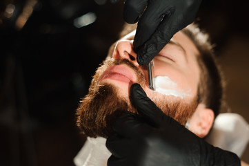 Master cuts hair and beard of men in the barbershop