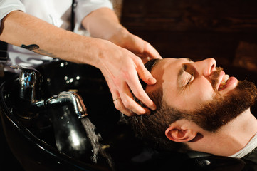 Master cuts hair and beard of men in the barbershop