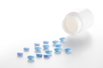 Medical blue pills and white bottle on white background. Concept of healthcare and medicine.