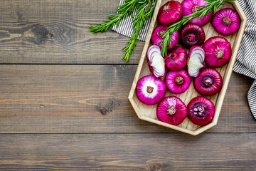 Red onion is healthy product. Onion bulbs in tray on dark wooden background top view copy space