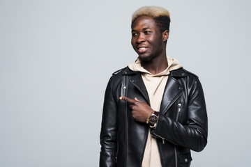 Portrait with empty place of sexy, virile, stunning man with beaming smile pointing forefinger to copy space, looking at camera, isolated on grey background