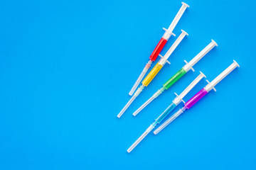 Vaccination, immunization. Syringe with colored medicament on blue background top view copy space