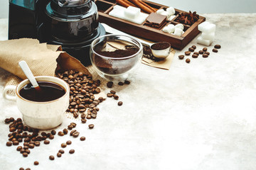 Variety things for prepare coffee. Roasted beans, ground coffee, scoop, electric coffee machine and assortment of sweets and spices to eat with on light background.