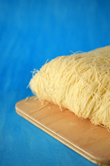 Kataifi dough on a wooden board on blue background