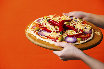 hands hold hot pizza with chili
