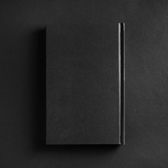Blank book cover on black paper background. Top view. Flat lay.