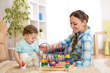 Naklejka premium Baby boy and mom play with educational toy in nursery at home.