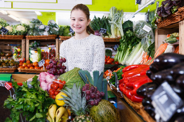 Cheerful girl in vegetable department of supermarket