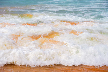 Blue waves of the ocean and yellow sand of the beach.
