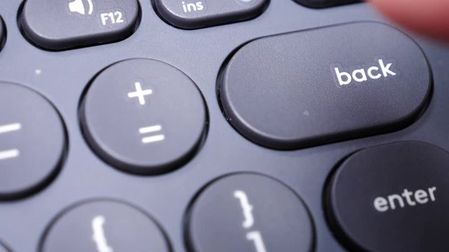 Closeup of finger pressing backspace button on the black computer keyboard. Technology. Slow motion