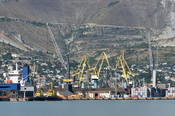 Landscape of the seaport with cranes. Seaport, cranes, containers, two tugs. Seaport in the background of mountains