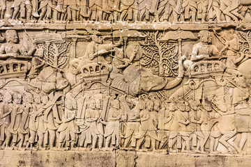 Fototapeta na wymiar Picturial stories of the Khmer army marching to war carved into the wall at the Unesco World Heritage site of Ankor Thom, Siem Reap, Cambodia