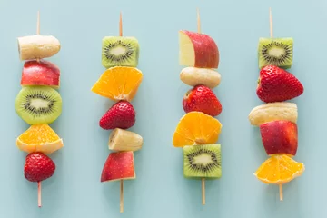 Zelfklevend Fotobehang fruit skewers the concept of healthy eating / pastel turquoise glass background. © Rochu_2008