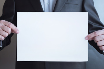 mock up in businessman's hand. male holding blank sheet of paper. young man in suit shows white card. Area for advertising. brochure flyer, space for template illustration, for text. Copy space