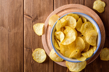 Potato chips in bowl on wooden table