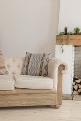 Beige sofa with pillows near the fireplace. Interior of the living room. Scandinavian style