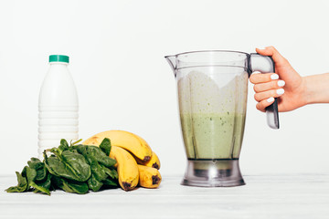 Woman's hand holds fresh made smoothie in a blender