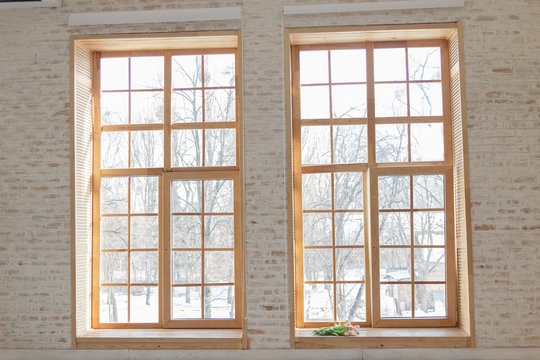 Large windows with wooden frames in a light beige wooden living room