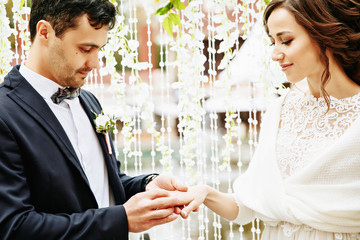 Newlyweds exchange rings during their beautiful wedding ceremony outdoors.