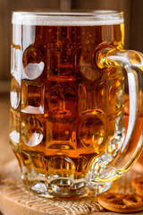 Mug of beer and snacks on wooden background