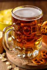 Mug of beer and snacks on wooden background