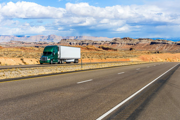 Desert Highway - A semi-trailer truck driving on Interstate Highway I-70 in colorful desert land,...