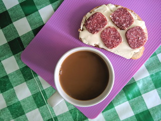 A sandwich with soft cheese and sausage, a snack, a purple kitchen board, a piece of bread on a green tablecloth, a home kitchen, a retro-style sandwich, American food, simple food