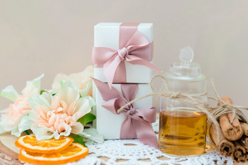 Made at home from orange oil with cinnamon perfume in a glass jar. Slices of dried orange, dried cinnamon and flowers. Gift box with jewelry charm bracelet is on the table. Present for every woman.