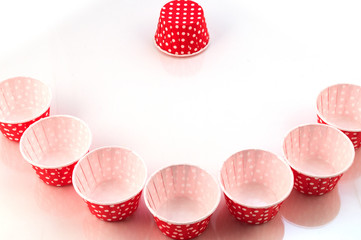 Several paper forms for baking confectionery products laid along a curve arc, one form is turned upside down.