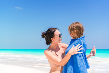 Happy mother and little girl on the beach vacation. Little in towel on the seashore