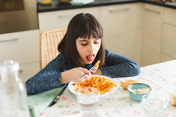 Little girl eating pasta at home