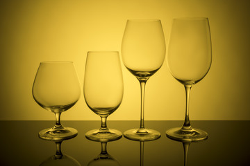 Glass glasses stand in a row on a yellow background.