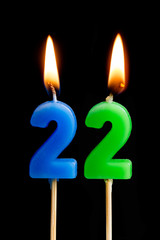 Burning candles in the form of 22 twenty two (numbers, dates) for cake isolated on black...