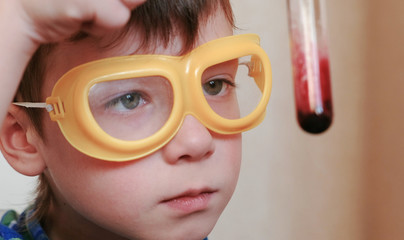 Experiments on chemistry at home. Closeup Boy's face examines the contents of the test tube.
