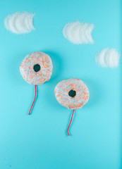 donuts on blue background, creative food minimalism, donut in a shape of balloon in the sky with...