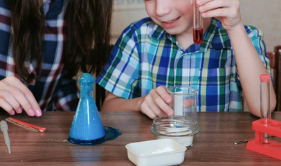 Chemistry experiments at home. Mom and son make a chemical reaction with the release of gas in the...