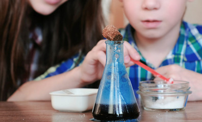 Chemistry experiments at home. Mom and son make a chemical reaction with the release of gas in the...