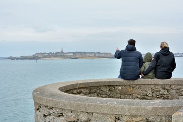 Un couple et son enfant assis à Dinard face à Saint-Malo en Bretagne