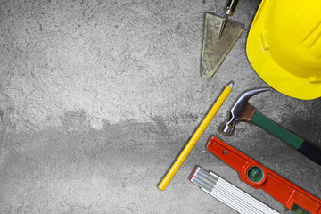 Protective helmet and mason tools  on background whit concrete wall 