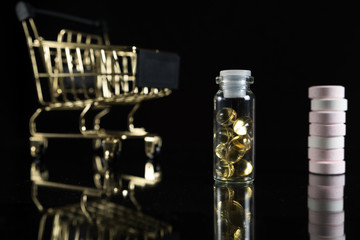 Medications and a gold shopping cart in the concept of expensive medicine. With copy space.