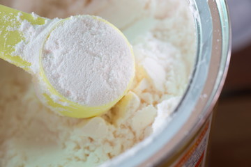 Milk powder for baby in measuring spoon on can.
